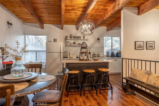 interior space featuring white cabinetry, hanging light fixtures, white refrigerator, dark hardwood / wood-style flooring, and beamed ceiling