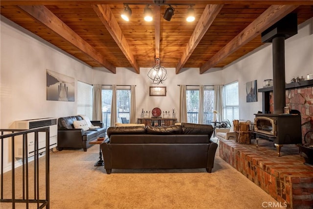 carpeted living room with beamed ceiling, a wood stove, a wealth of natural light, and wood ceiling