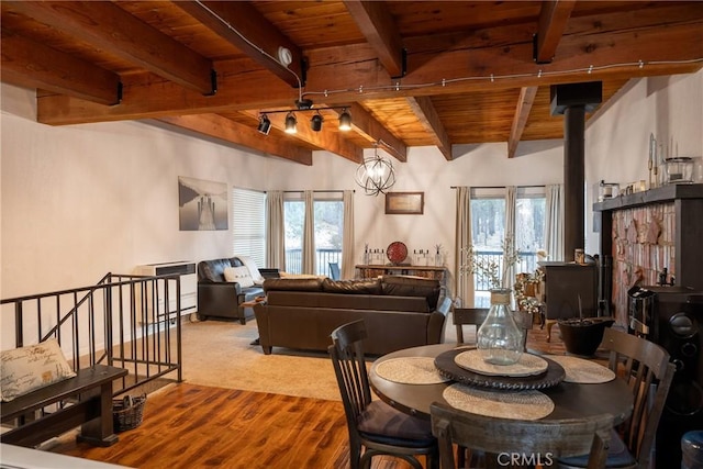 dining room featuring wood ceiling, beamed ceiling, plenty of natural light, and a wood stove