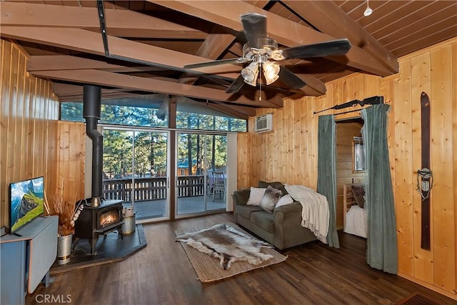 living room featuring dark wood-type flooring, lofted ceiling with beams, a wood stove, wooden walls, and ceiling fan