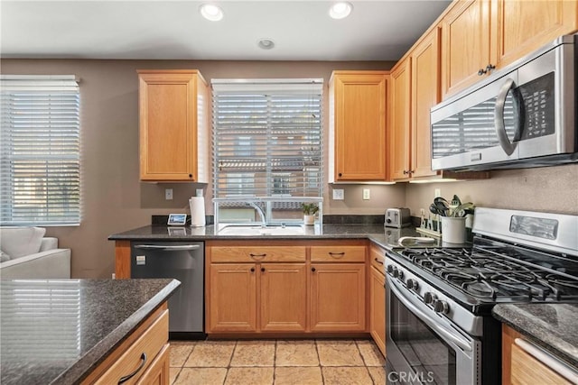 kitchen featuring light tile patterned floors, appliances with stainless steel finishes, sink, and dark stone counters