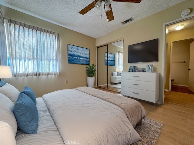 bedroom with a textured ceiling, a closet, ceiling fan, and light wood-type flooring