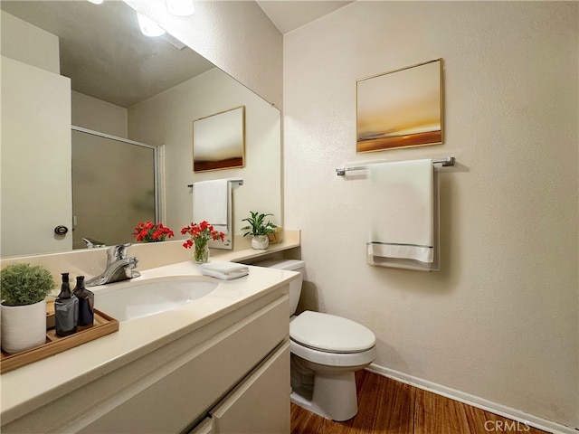 bathroom featuring wood-type flooring, toilet, a shower with door, and vanity