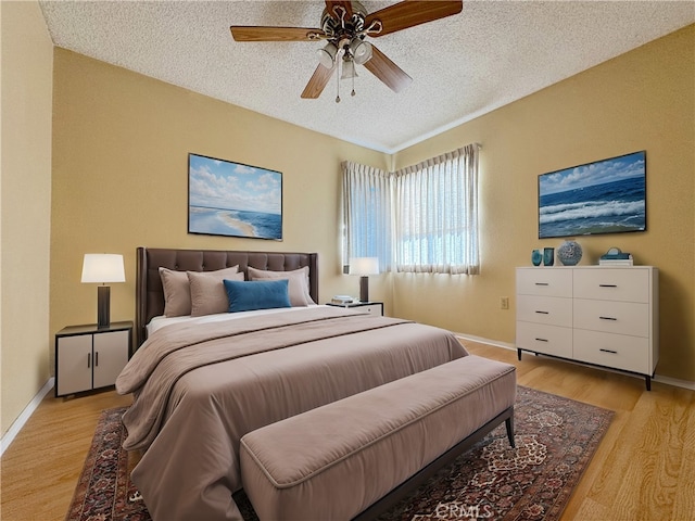 bedroom with ceiling fan, a textured ceiling, and light wood-type flooring