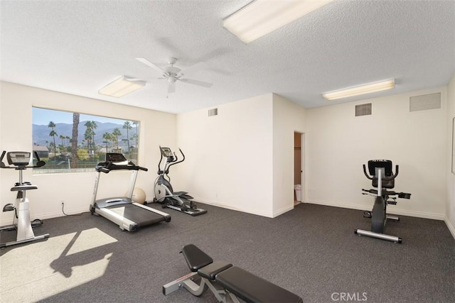 exercise area featuring ceiling fan and a textured ceiling