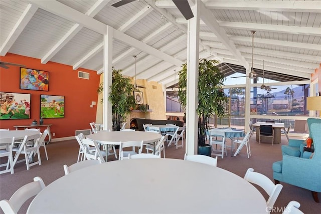 carpeted dining area with ceiling fan and vaulted ceiling with beams