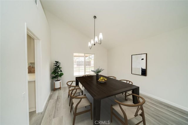 dining room featuring vaulted ceiling, light hardwood / wood-style floors, and a chandelier