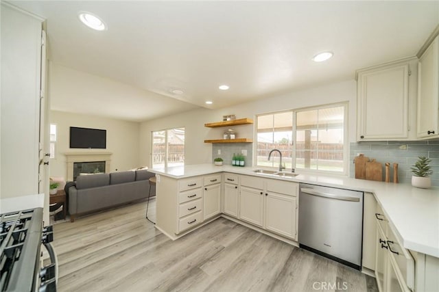 kitchen with sink, dishwasher, decorative backsplash, kitchen peninsula, and light wood-type flooring