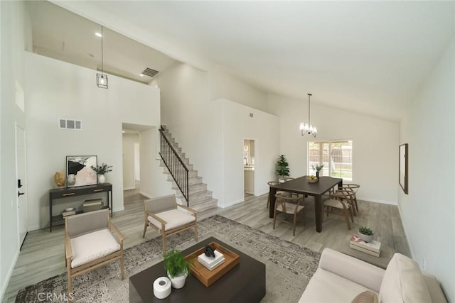 living room featuring an inviting chandelier, high vaulted ceiling, and light hardwood / wood-style flooring