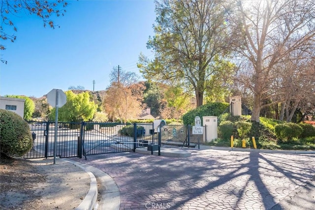 view of street with curbs, a gated entry, traffic signs, and a gate