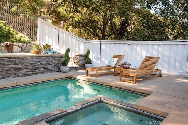 view of swimming pool with a patio area, a pool with connected hot tub, and a fenced backyard