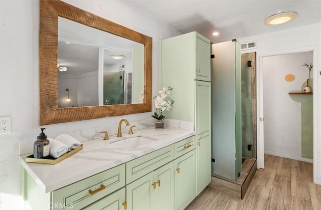 bathroom with a stall shower, visible vents, wood finished floors, and vanity