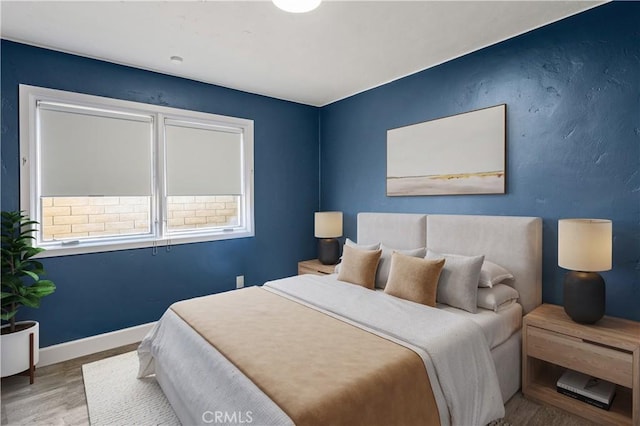 bedroom featuring multiple windows, baseboards, and wood finished floors