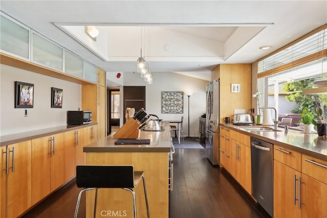 kitchen featuring a kitchen island, appliances with stainless steel finishes, pendant lighting, a kitchen bar, and dark wood-type flooring