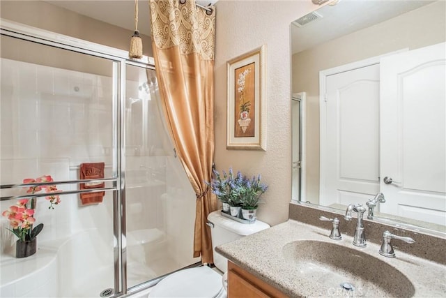 bathroom featuring vanity, toilet, and a shower with shower door