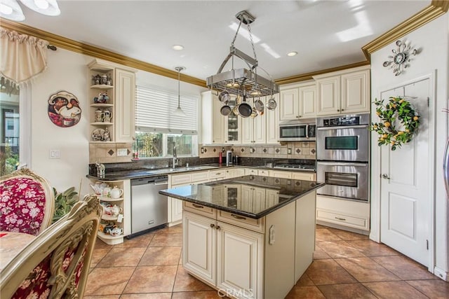 kitchen featuring a kitchen island, appliances with stainless steel finishes, decorative light fixtures, dark stone counters, and cream cabinets