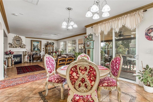 tiled dining area with a tile fireplace, ornamental molding, and ceiling fan with notable chandelier