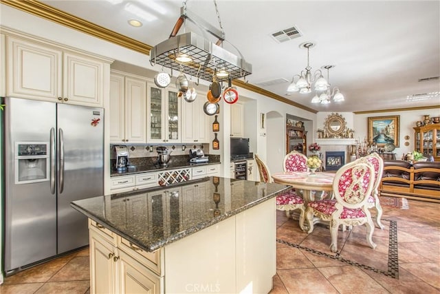 kitchen with a kitchen island, pendant lighting, stainless steel fridge, light tile patterned floors, and cream cabinets