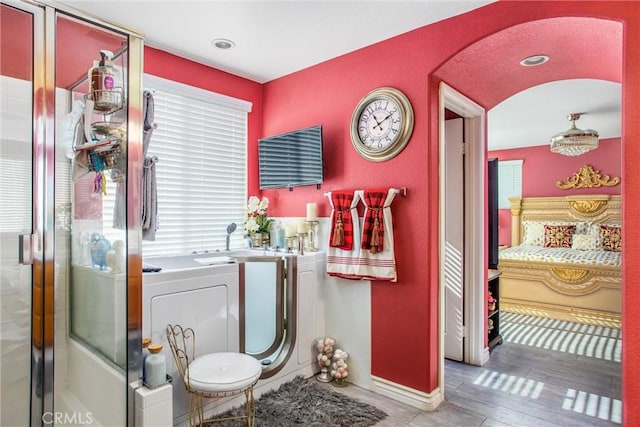 bathroom with hardwood / wood-style floors, a shower with door, and washing machine and dryer