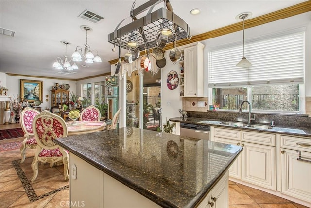 kitchen featuring sink, decorative light fixtures, a center island, a wealth of natural light, and dark stone counters