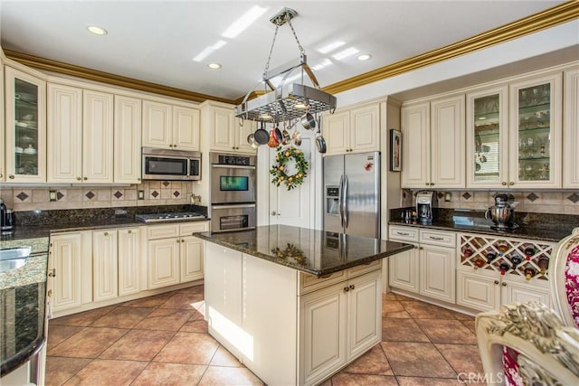 kitchen featuring cream cabinetry, a kitchen island, dark stone counters, and appliances with stainless steel finishes