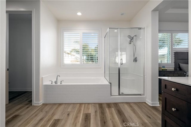 bathroom featuring wood-type flooring, plus walk in shower, and vanity