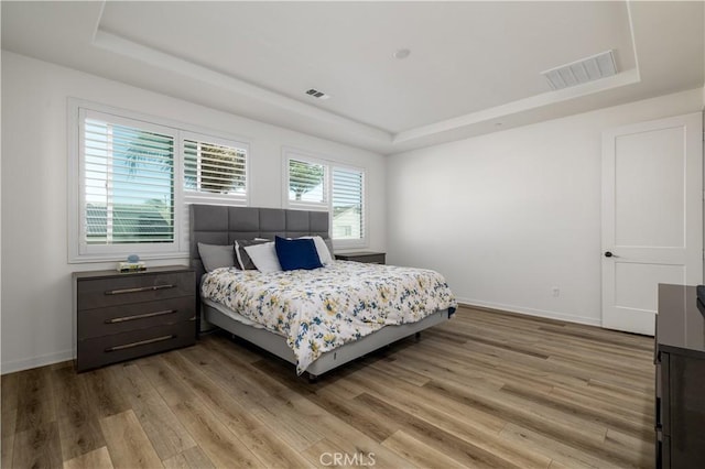 bedroom with hardwood / wood-style flooring and a tray ceiling