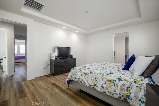 bedroom featuring hardwood / wood-style floors and a tray ceiling