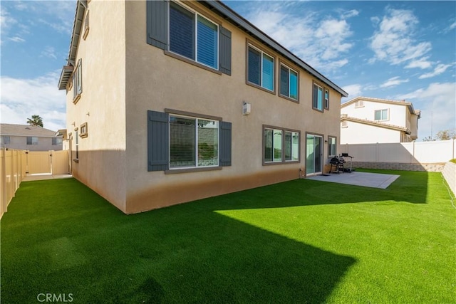 back of house featuring a lawn and a patio area