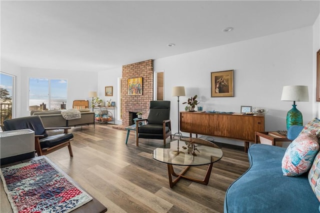 living room with wood-type flooring and a brick fireplace