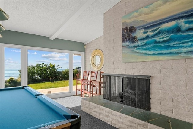 recreation room with a tile fireplace, carpet, vaulted ceiling with beams, and a textured ceiling