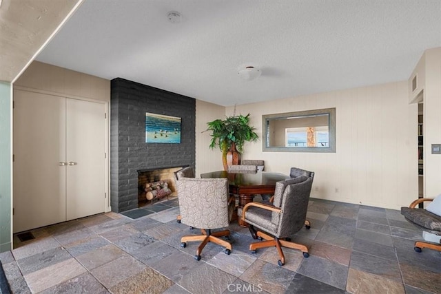 dining area featuring a brick fireplace and a textured ceiling