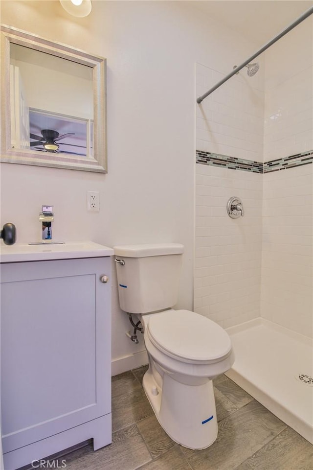 bathroom with vanity, a tile shower, and toilet