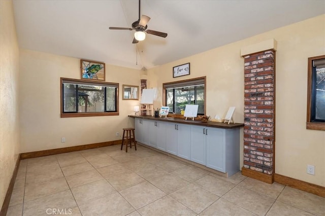 interior space featuring lofted ceiling, light tile patterned floors, white cabinets, and ceiling fan