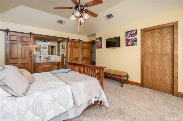 bedroom featuring a barn door, light colored carpet, and ceiling fan