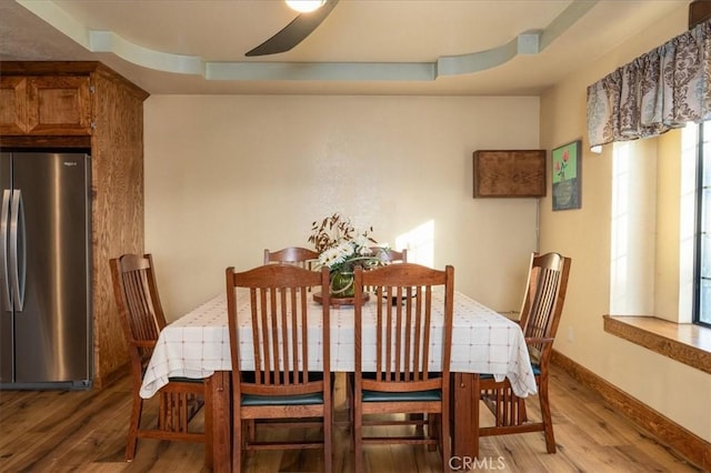 dining area with a tray ceiling, wood-type flooring, and ceiling fan