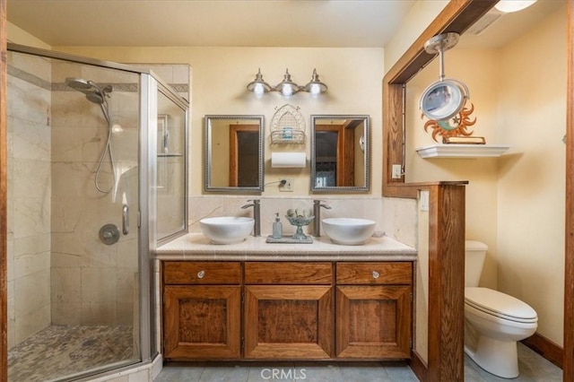 bathroom featuring tasteful backsplash, vanity, toilet, and a shower with door