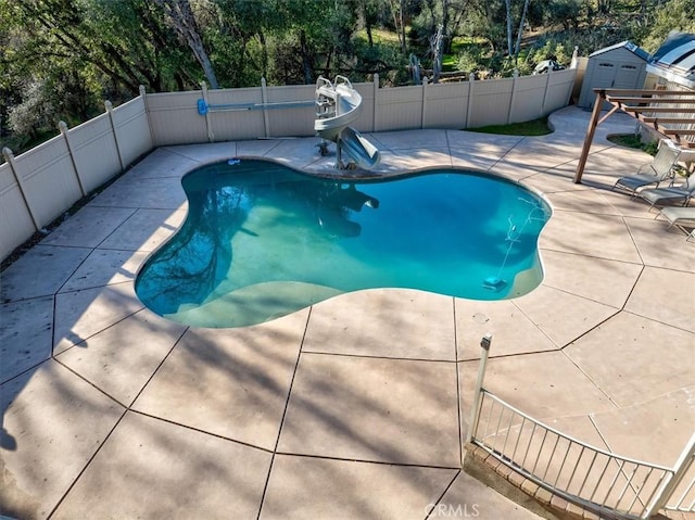 view of swimming pool featuring a shed and a patio area