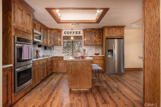 kitchen featuring a kitchen island, a breakfast bar area, decorative backsplash, stainless steel appliances, and light hardwood / wood-style flooring