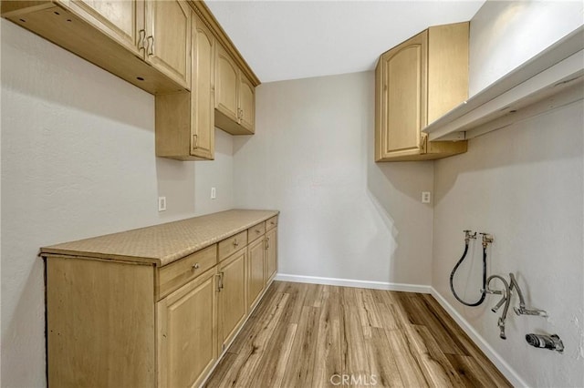 clothes washing area featuring cabinets and light wood-type flooring