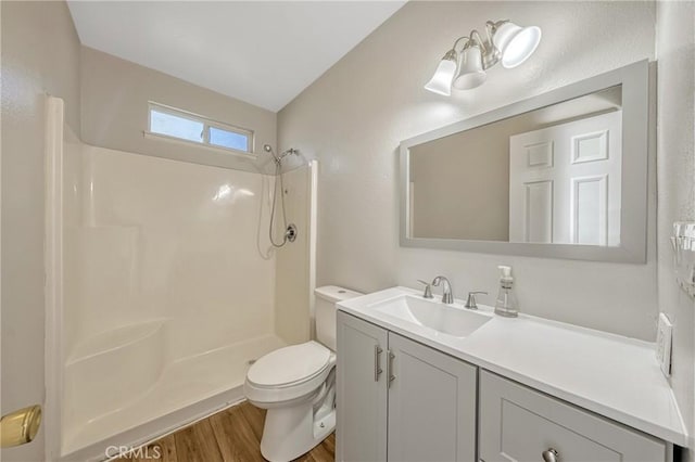 bathroom with a shower, hardwood / wood-style floors, vanity, and toilet