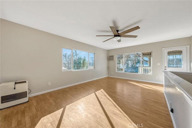 interior space with heating unit, ceiling fan, and light wood-type flooring