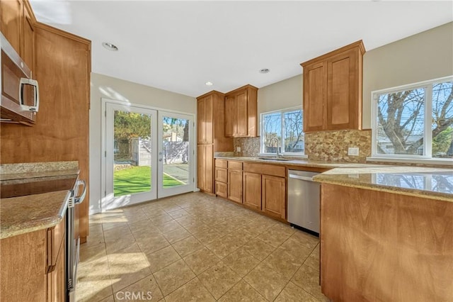 kitchen featuring tasteful backsplash, sink, light tile patterned floors, light stone counters, and stainless steel appliances