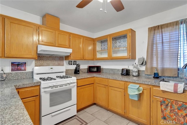 kitchen featuring ceiling fan, sink, white gas stove, and light tile patterned floors