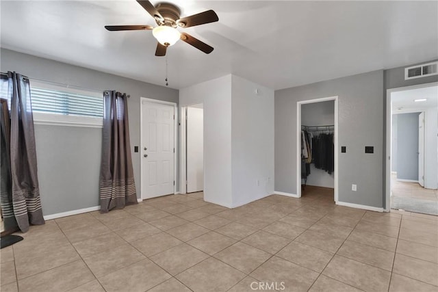 interior space featuring light tile patterned floors, a spacious closet, and ceiling fan