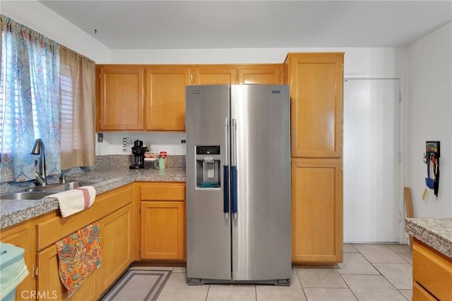 kitchen featuring high end fridge, sink, and light tile patterned floors