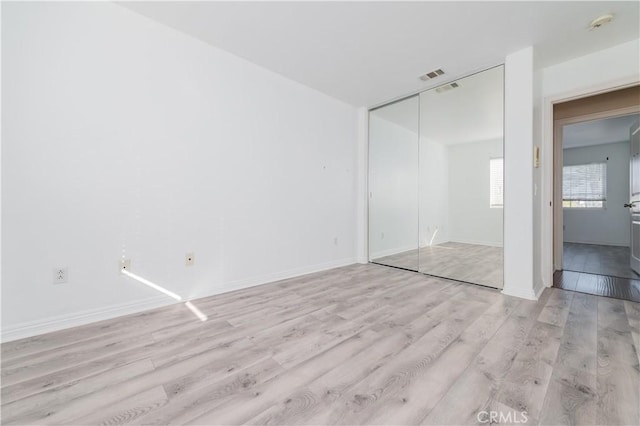 unfurnished bedroom with light wood-type flooring and a closet