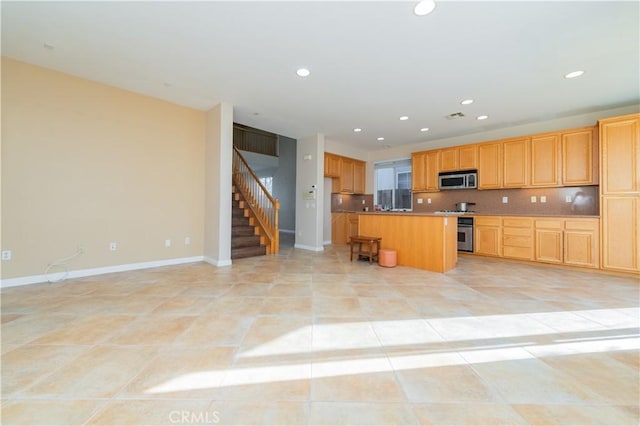 kitchen with a kitchen island, appliances with stainless steel finishes, a kitchen bar, decorative backsplash, and light tile patterned floors