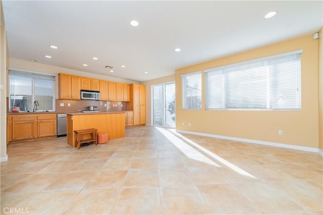 kitchen with sink, a breakfast bar area, appliances with stainless steel finishes, tasteful backsplash, and a kitchen island