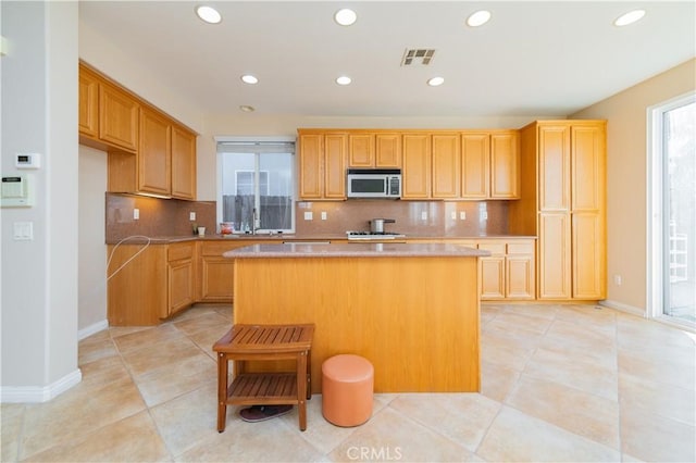 kitchen with a center island, decorative backsplash, and light tile patterned floors